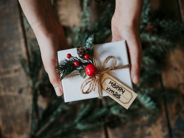 Eine Person hält ein verpacktes Geschenk in der Hand.