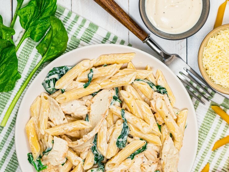 Pasta mit Parmesan-Spinat-Creme auf Teller angerichtet.