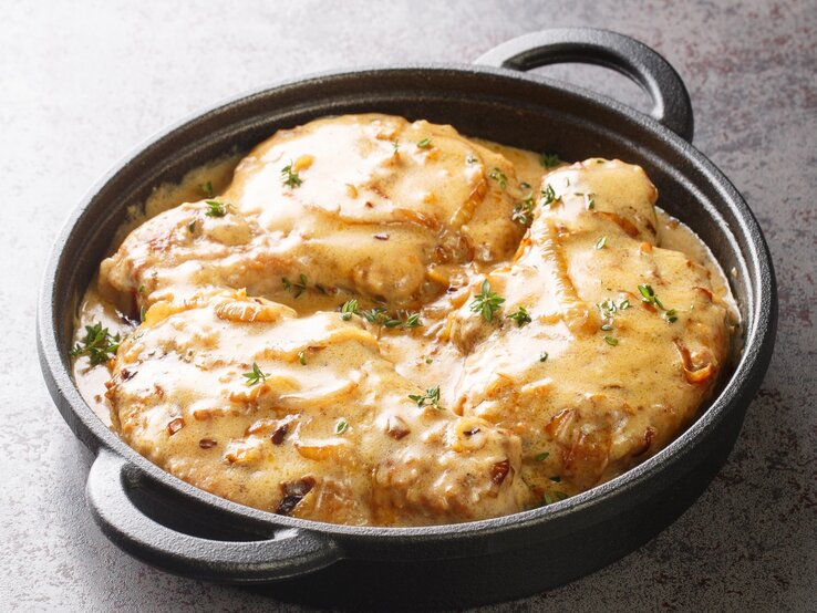 Schwarze gusseiserne Pfanne gefüllt mit Zwiebel-Sahne-Schnitzel.