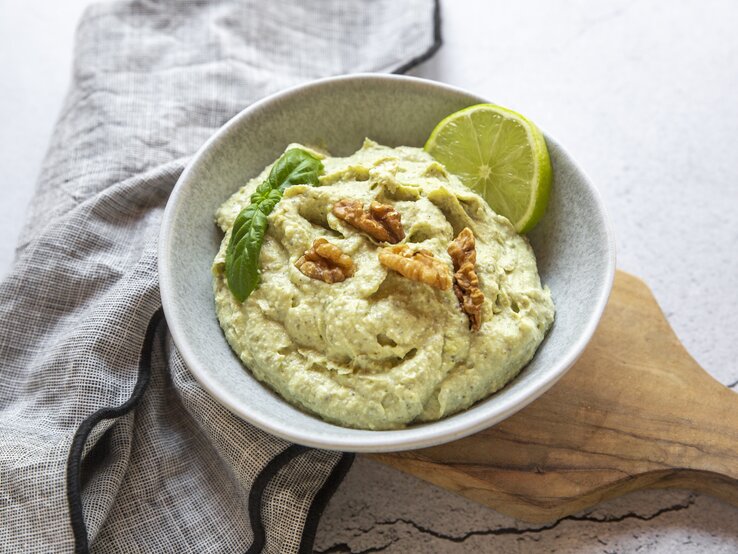 Schale mit Feta-Avocado-Creme mit Walnuss auf hellem Untergrund. 