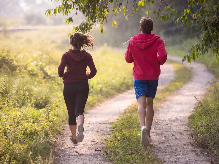 Ein junges Paar joggt über einen Feldweg.