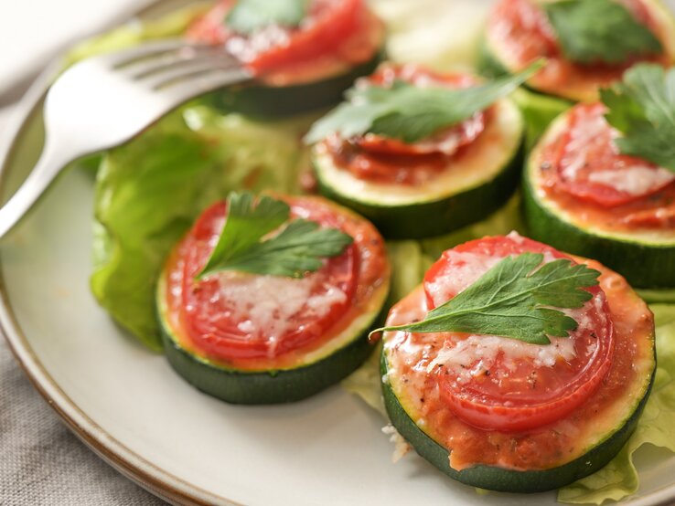 Zucchini-Bruschetta-Häppchen auf einem Teller, daneben eine Gabel.