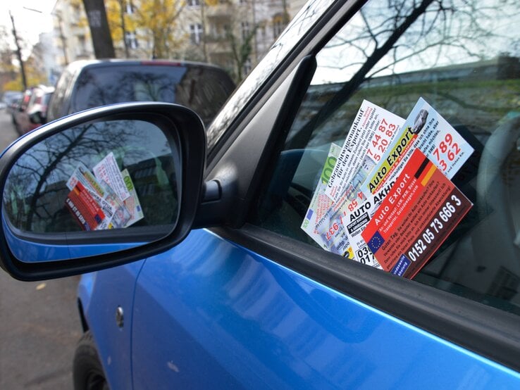 Geparktes, blaues Auto mit Ankaufkarten an der Scheibe.