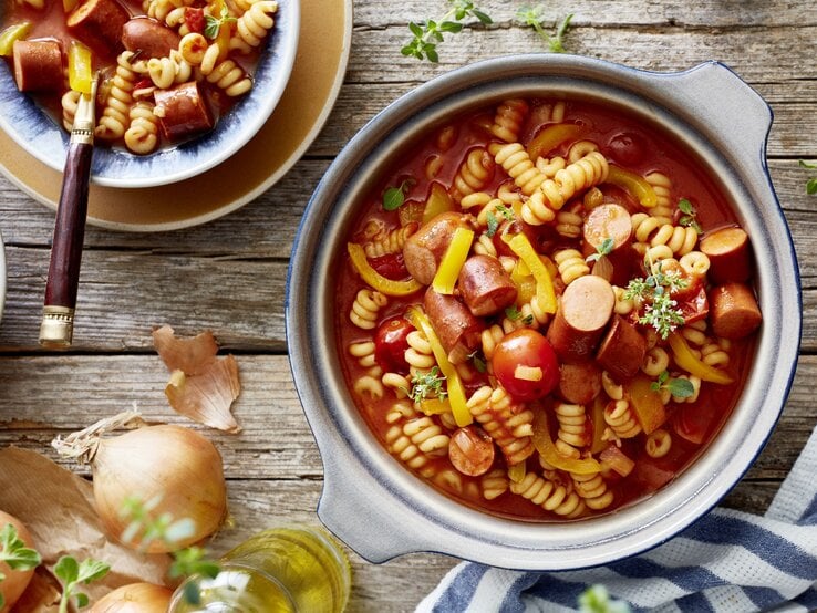 One-Pot-Wurstgulasch in Topf auf Holztisch. 