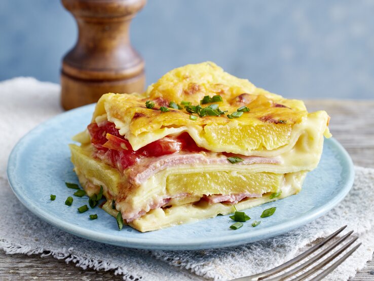 Lasagne Hawaii auf einem blauen Teller auf hölzernem Hintergrund. 