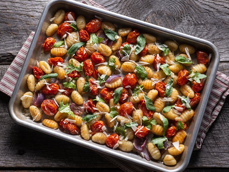 Gnocchi vom Blech mit italienischem Gemüse auf grauem Holz. 