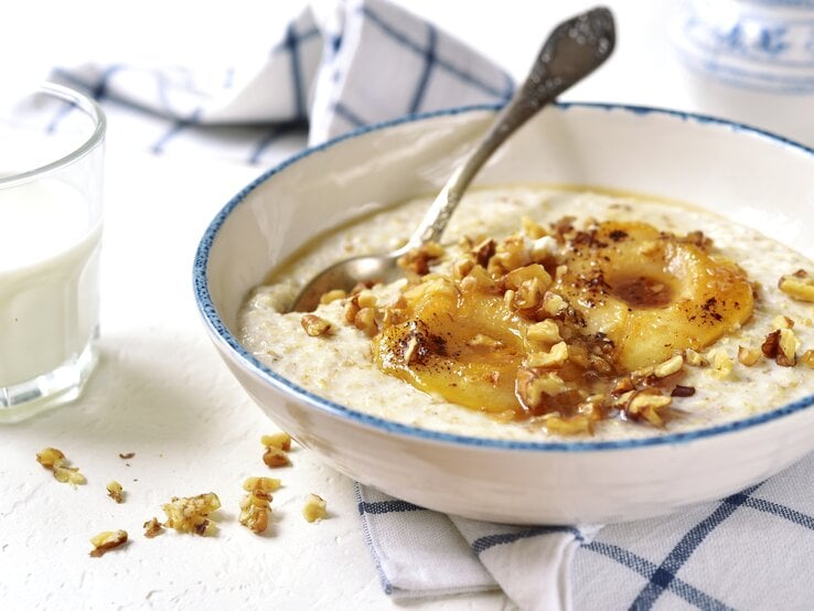 Eine weiße Schüssel mit Vanille-Porridge mit karamellisierten Birnen.