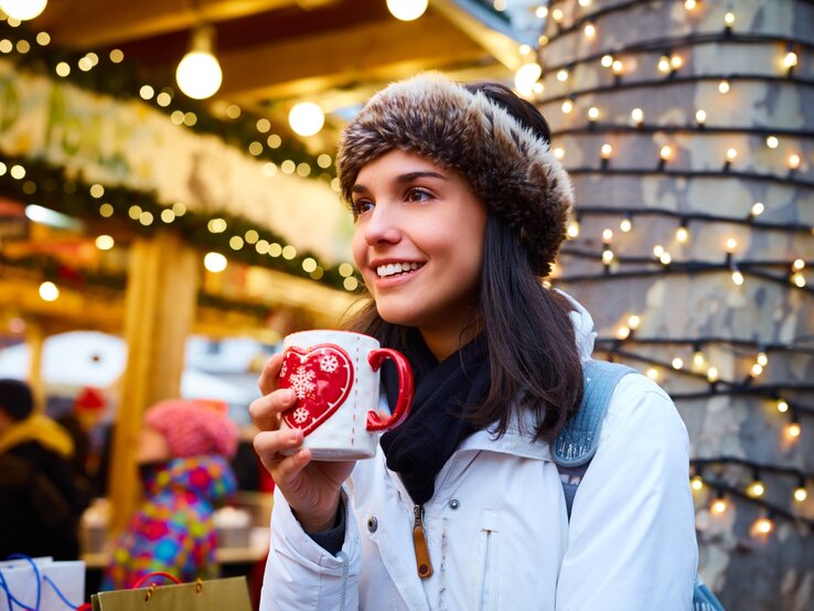 Frau trinkt Glühwein auf dem Weihnachtsmarkt