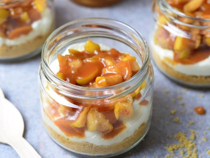 Mehrere Dessertgläser mit dem Schichtdessert auf einem hellgrauen Untergrund von schräg oben fotografiert.