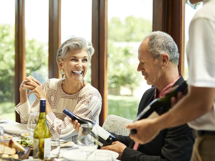 Zwei ältere Personen im Restaurant beim Weinprobieren.