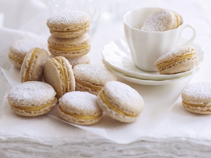 Zimt-Eierlikör-Macarons, serviert auf einem weißen Küchentuch mit einer Tasse Kaffee. 