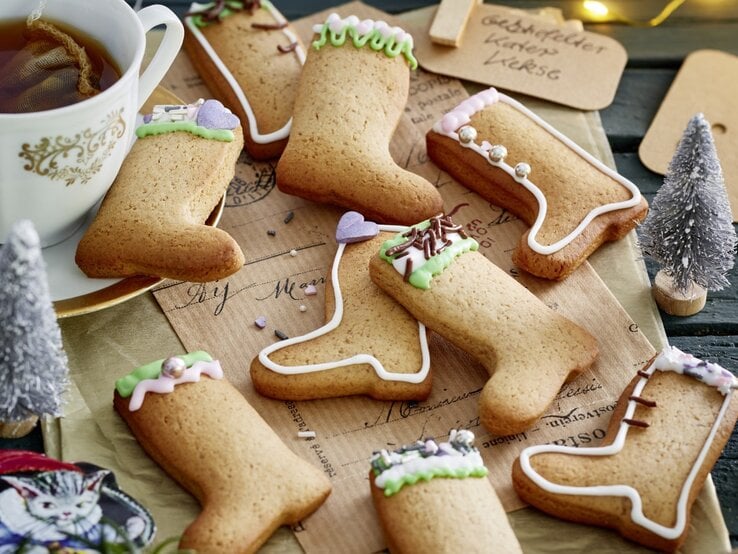 Auf einem Weihnachtstisch liegen meherer Gestiefelter-Kater-Kekse. Sie sind mit buntem Zuckerguss dekoriert.