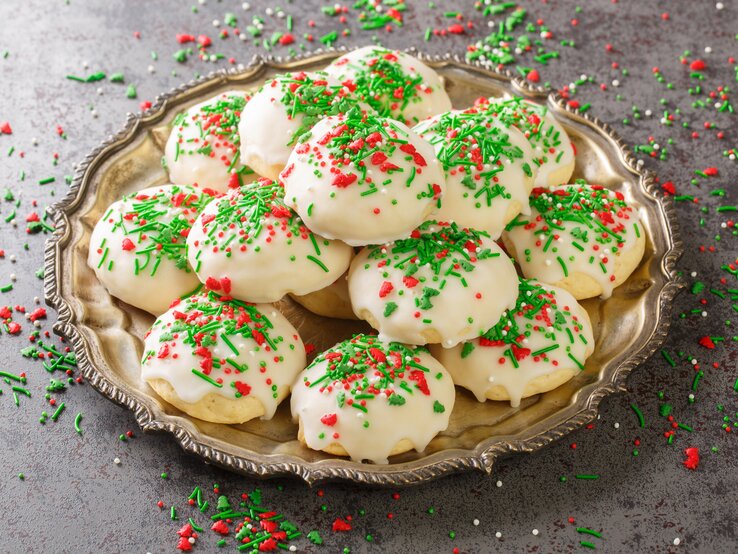 Runde Plätzchen mit Zuckerguss und bunten Streuseln auf Teller.  | © Getty Images/ALLEKO