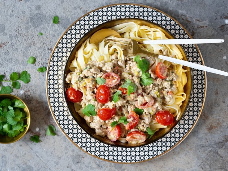 Ein Teller Hähnchenbolognese Bianco der Familie Geiss in der Draufsicht, daneben steht ein Schälchen frischer Petersilie.