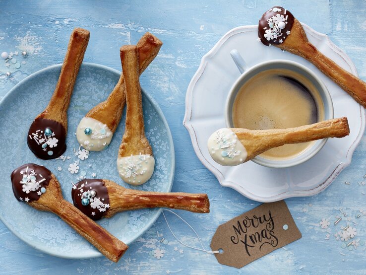 Spekulatius-Löffel-Plätzchen auf blauen Tellern auf blauem Untergrund. 