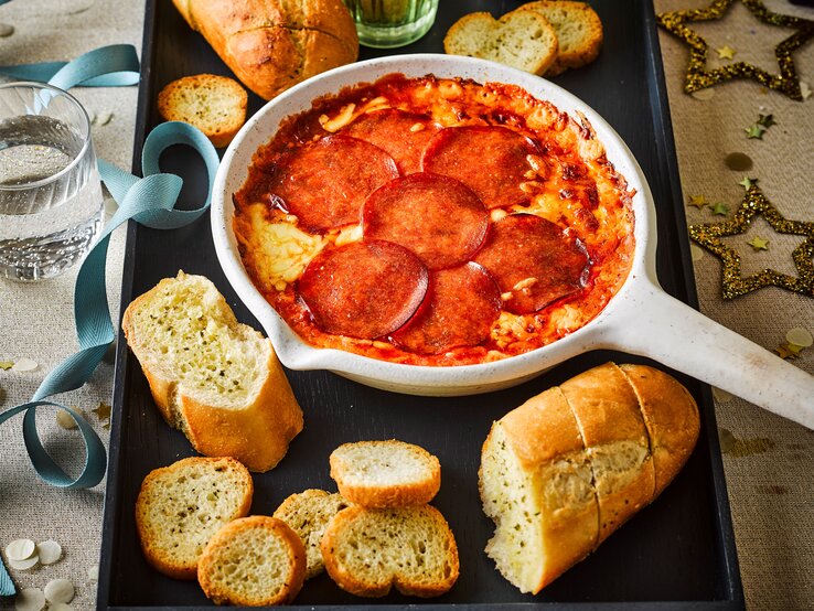 Pizza-Fondue-Dip mit Baguette aufgetischt.