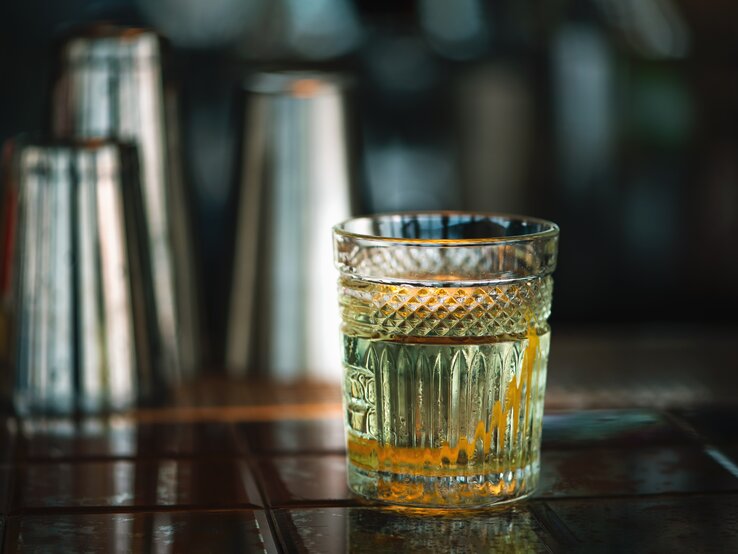 Ein Rührglas gefüllt mit weißem Negroni auf einer Bar. 