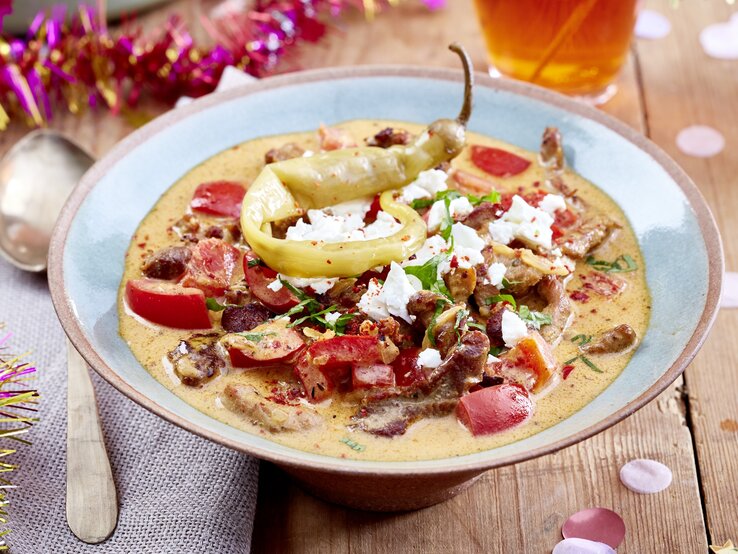 Ein Teller Gyrossuppe mit Feta, drumherum etwas Partydeko.