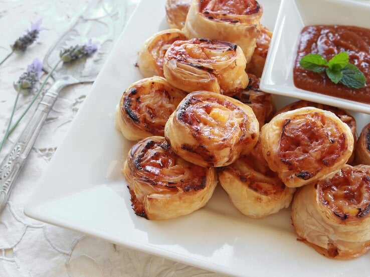 Mehrere Blätterteig-Schnecken mit Hawaii-Füllung auf einem weißen Teller. 