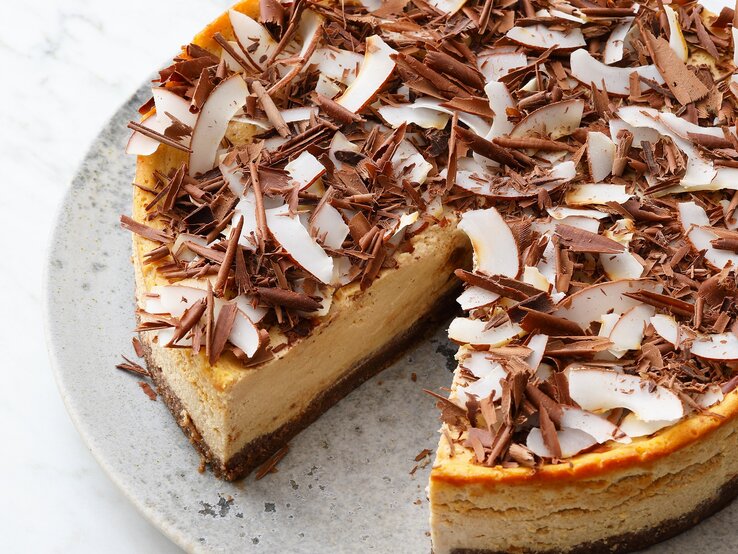 Der Kuchen mit einem ausgeschnittenen Stück auf einem grauen Teller von schräg oben fotografiert.