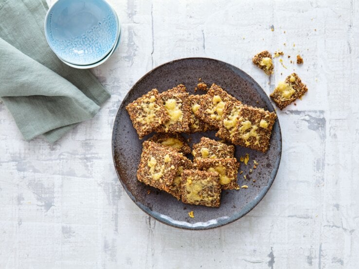 Low-Carb-Knäckebrot Ein schwarzer Teller mit dem Knäckebrot direkt von oben fotografiert.