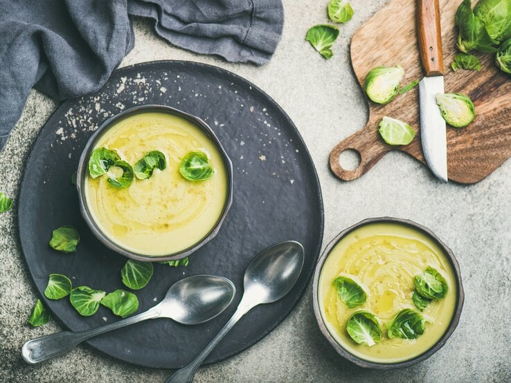 Rosenkohlsuppe Draufsicht auf eine runde Schüssel gefüllt mit einer cremigen Suppe aus Rosenkohl. Das Ganze steht auf einem runden untersetzer.