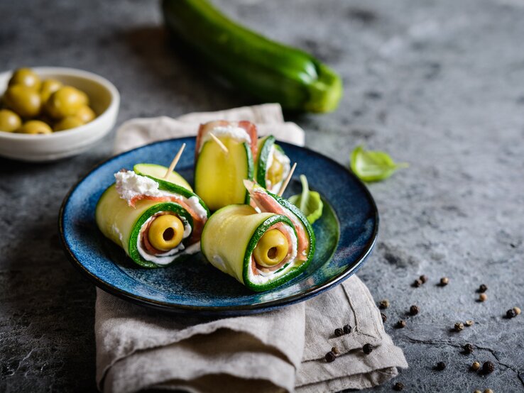 Gerollte Zucchini gefüllt mit Oliven, Schinken und Käse, fixiert mit einem Zahnstocher