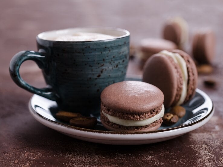 Süße Tiramisu-Kekse auf blauem Teller mit Kaffeetasse vor braunem Hintergrund