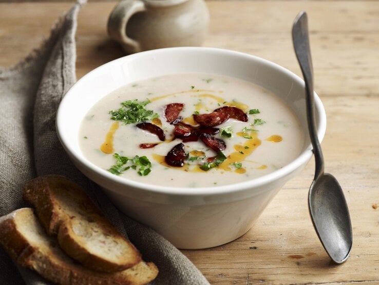 Draufsicht: Eine Schüssel mit einer Bohnensuppe, die mit Wurstscheiben zubereitet wird.