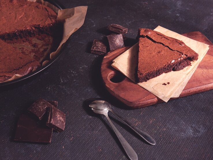 Angeschnittener Schokokuchen auf dunklem Untergrund. 