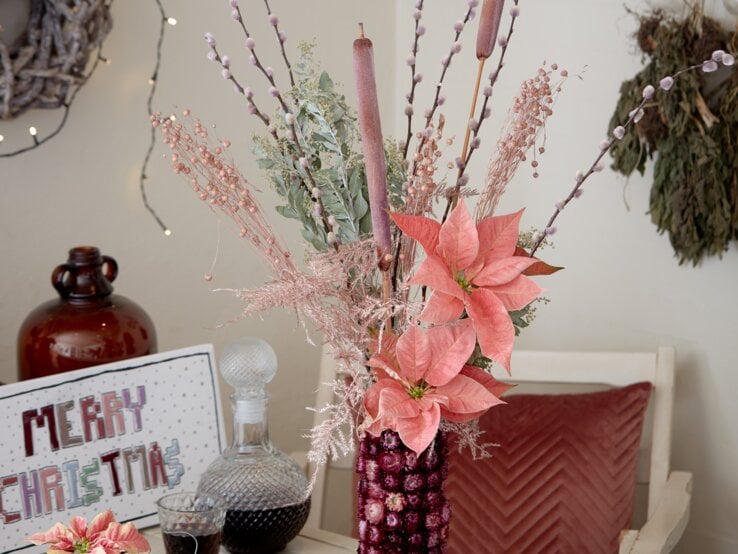 Winterlicher Tischschmuck in der Vase mit Weihnachtssternblüten. | © starsuniteeurope.eu