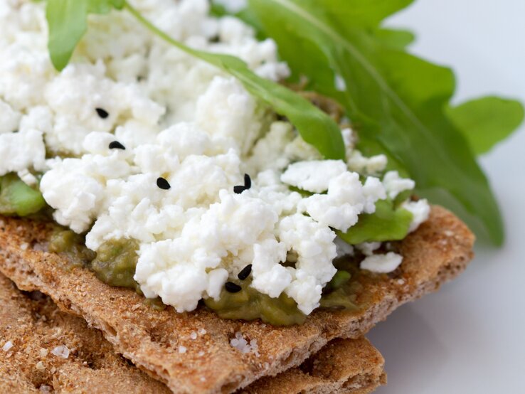 1 Scheibe Knäckebrot (12 g) mit 1 EL Kräuterquark (30 % Fett) und 10 g Rucola hat 70 kcal. | © iStock/kornyeyeva