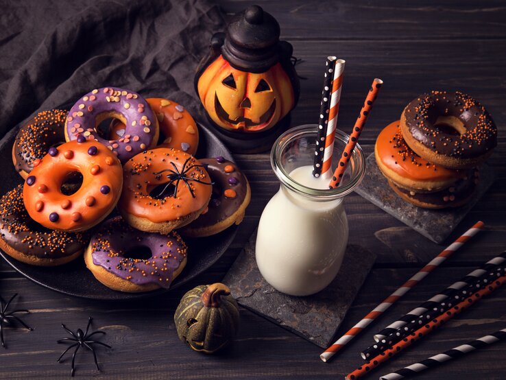 verschieden dekortierte Halloween-Donuts auf einem Teller. 