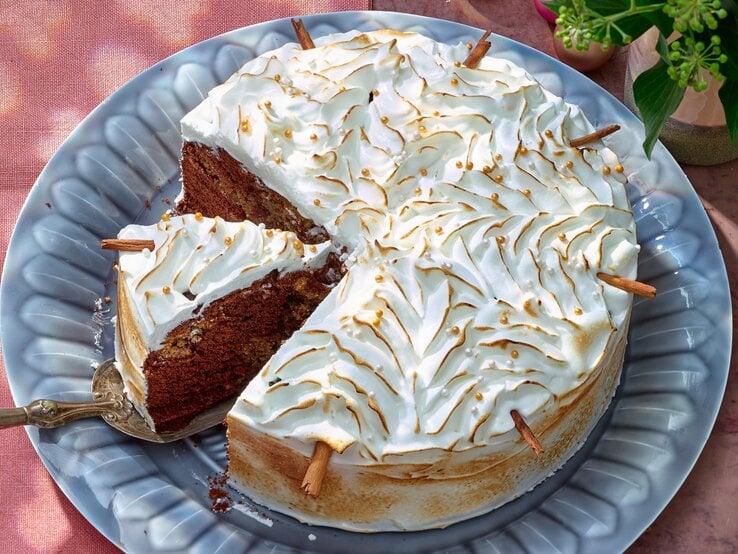 Zimtstern-Marmorkuchen mit Baiserhaube auf einem blauen Teller auf rosa Hintergrund. 