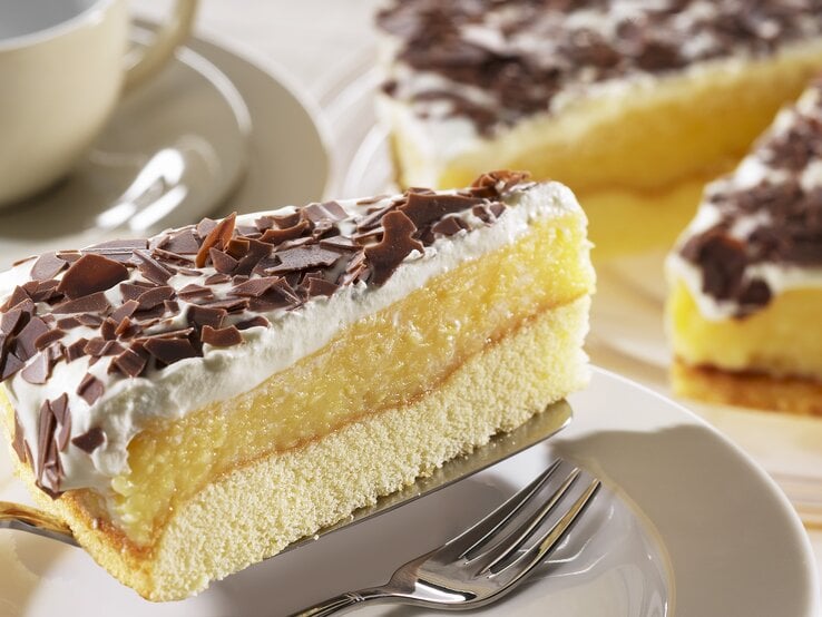 Ein Stück der schwedische Apfeltorte mit Sahne und Schokoraspeln auf einem Kuchenteller von schräg oben fotografiert. 