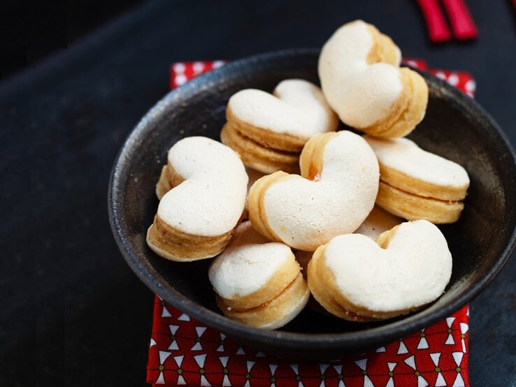 Herzförmige Baiser-Plätzchen in schwarzer Schale. 