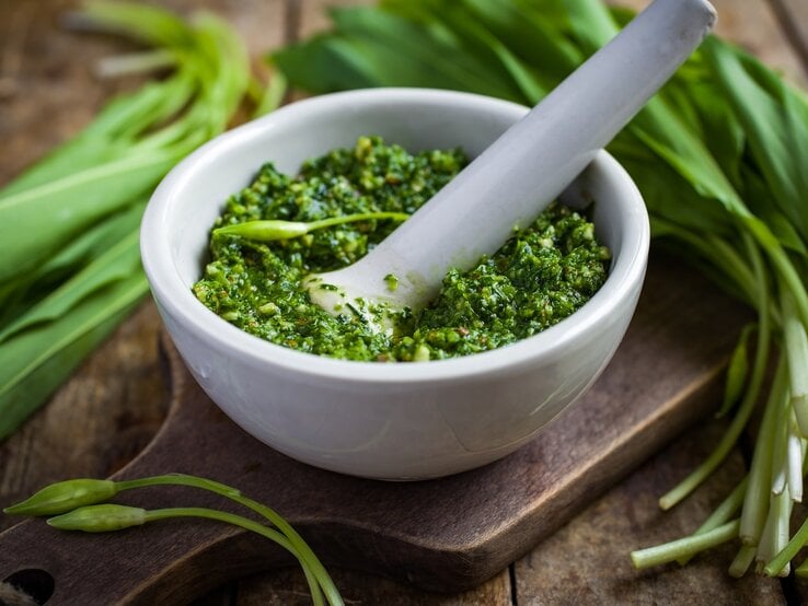 Weißer Mörser gefüllt mit hausgemachtem Bärlauchpesto. 