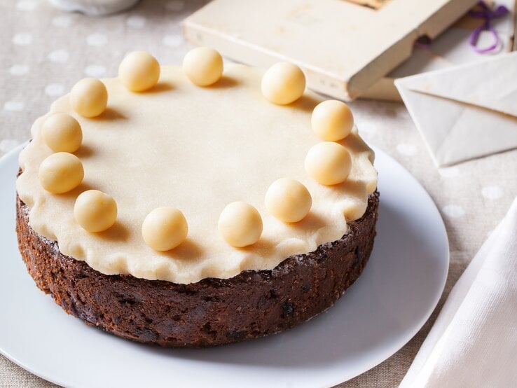 Runder Kuchen mit einer Marzipanschicht und runden Marzipan-Kugeln belegt. 