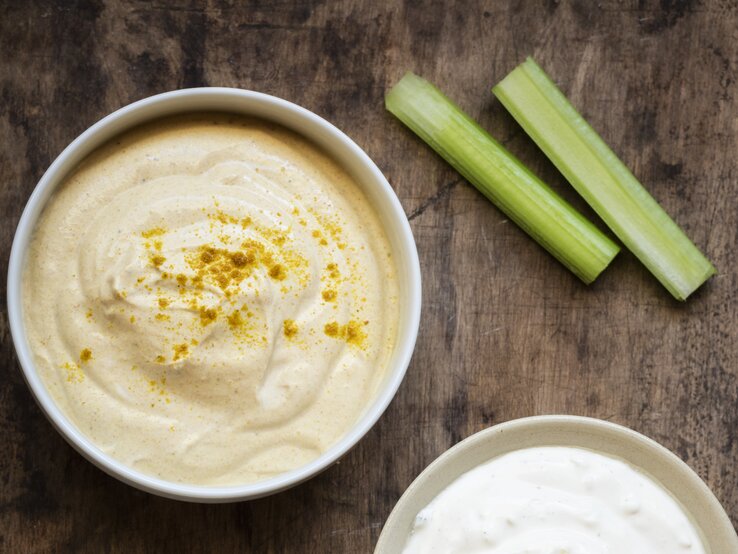 Curry-Dip mit Rohkost auf hölzernem Untergrund.