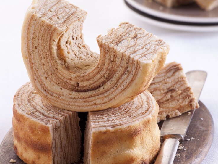 Mehrere Stücken vom Baumkuchen auf hellem Untergrund. Alles von schräg oben fotografiert.