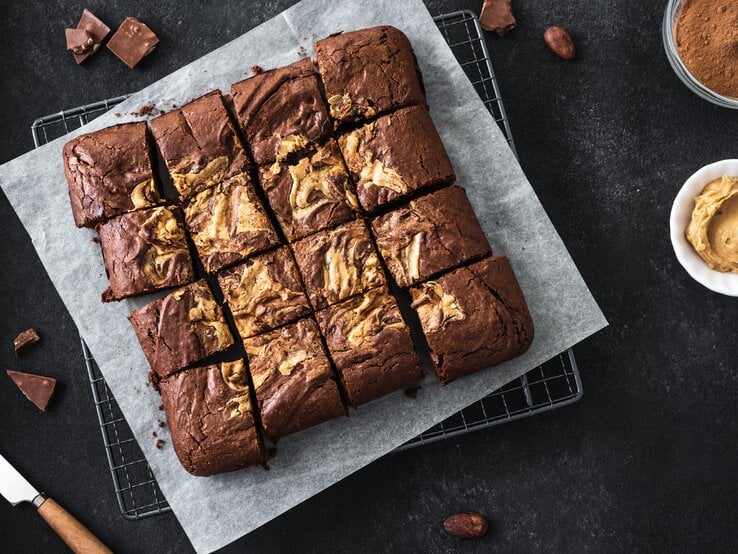 Draufsicht auf Erdnussbutter-Schokobutter-Brownies auf dunklem Tisch. 