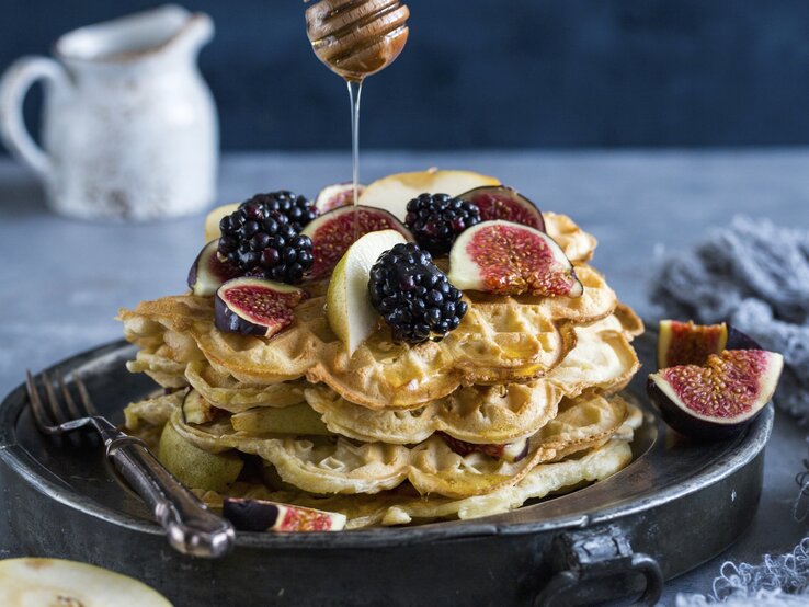 Die Joghurt Waffeln auf einem schwarzen Teller mit grauem Hintergrund. Alles von der Seite fotografiert.