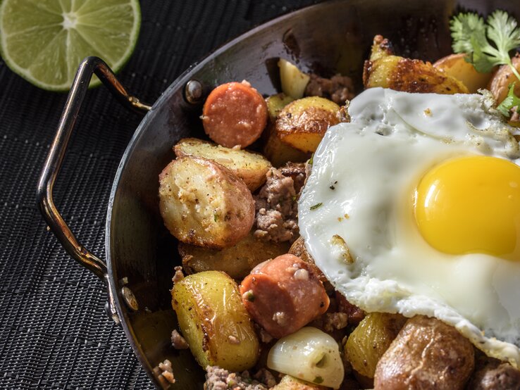 Deftige Kartoffelpfanne mit Würstchen und Hack garniert mit Spiegelei. 