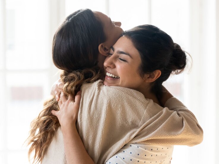 Zwei Frauen umarmen sich innig und lächeln dabei