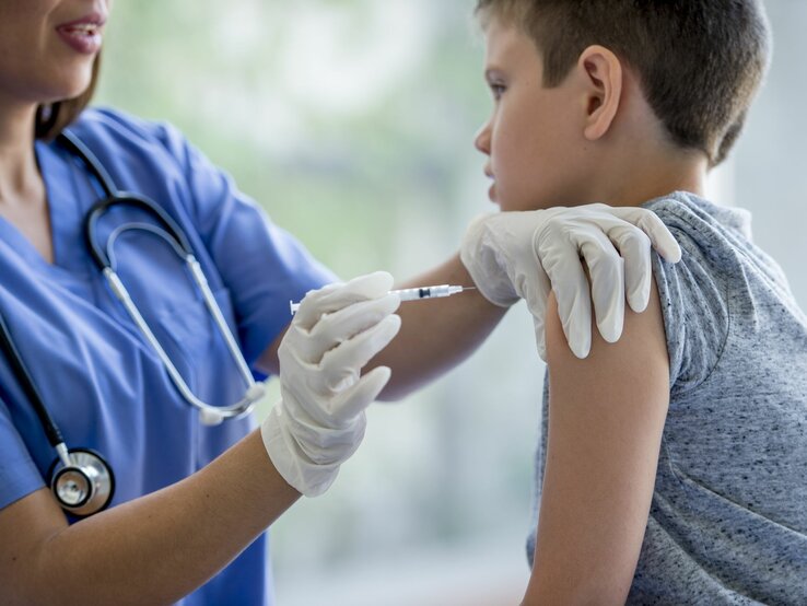 Ein Junge bekommt von einer Krankenschwester eine Impfspritze in den Oberarm.