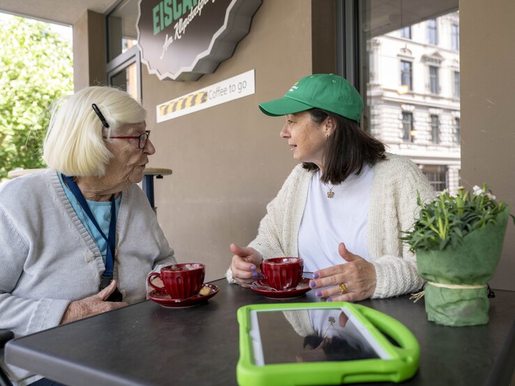 Preisträgerin Mitra Kassai mit einer Seniorin im Gespräch an einem Tisch