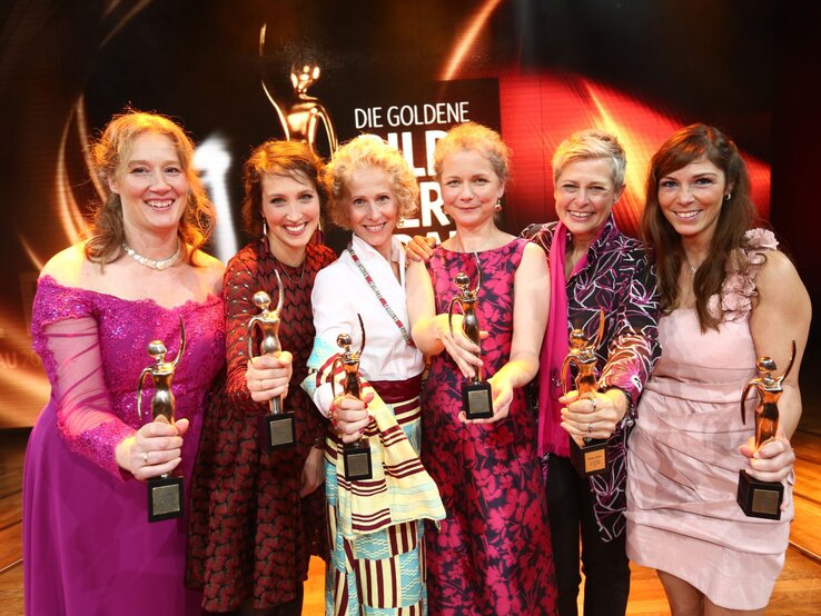 Sechs Preisträgerinnen der GOLDENEN BILD der FRAU-Gala 2017 halten in Abendgarderobe ihren goldenen Preis in die Kamera 