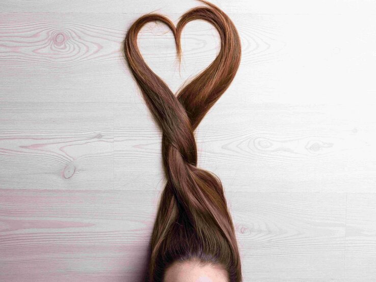 Braune lange Haare, die auf dem Boden liegen und zu einem Herz geformt sind. | © Giulio Fornasar via Gettyimages