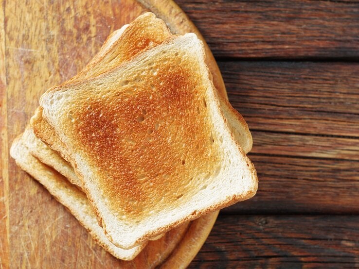 Mehrere getoastete Scheiben Toastbrot auf einem Holzbrett. 