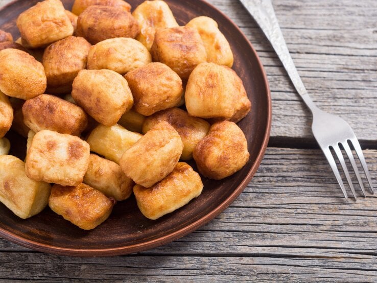 Kross frittierte Gnocchi auf braunem Teller auf einem Holztisch. 